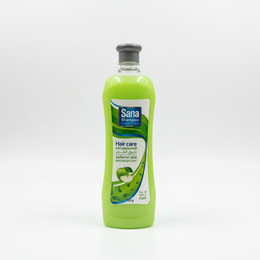 Two bottles of Sana shampoo, one green and one orange, on a grass-like surface with a store shelf in the background.