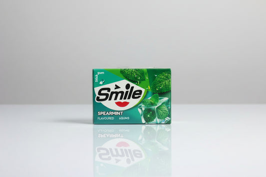 Three packs of Smile Spearmint chewing gum tied together with red string on a light gray background.